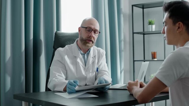 Bearded doctor in gloves shows x-ray picture to patient