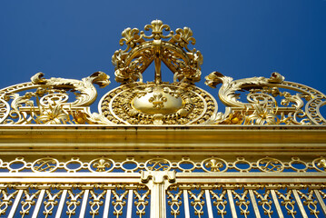 Golden gate with beautiful ornaments at the entrance of Palace of Versailles on a sunny spring day....