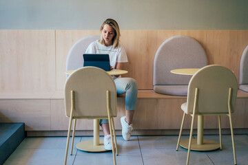 Modern woman freelancer working on a laptop at a table in a coworking space. Remote online work