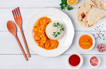Chicken curry with rice and chapati flatbread, a traditional Indian dish, on a wooden table, no people, selective focus,