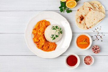 Chicken curry with rice and chapati flatbread, a traditional Indian dish, on a wooden table, no people, selective focus,