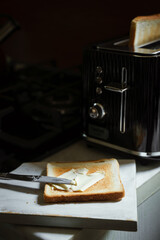 Spreading butter over toasted bread for breakfast. Retro toaster in the background
