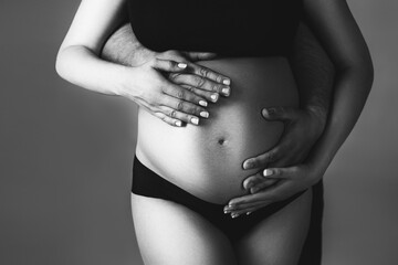 Men's and women's hands on a pregnant belly