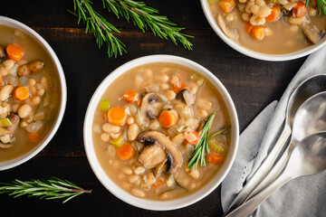Creamy Mushroom, White Bean and Rosemary Soup: Bowls of soup made with navy beans, mushrooms, and other vegetables