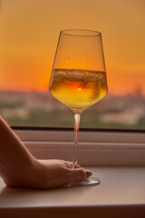 A woman's hand with a glass of wine on the background of a bright sunset.