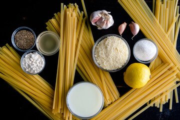 Fettuccine Alfredo Ingredients on a Wood Background: Raw pasta, garlic, parmesan cheese, and other...