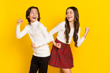 Photo portrait of small kids smiling gesturing like winners isolated on bright yellow color background