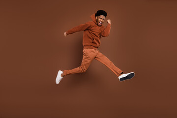 Fototapeta na wymiar Full size profile photo of yell short hairdo young guy run dress sportswear trousers sneakers isolated on brown background