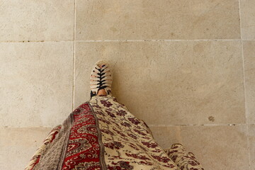 Woman's foot with sandal and long skirt stepping forward.