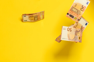 Rain of euro bills, flying falling money on a yellow background, European currency in the face of...