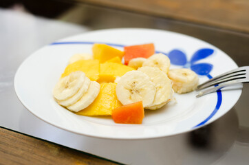 Plato de fruta fresca para desayuno, almuerzo comida o postre saludable. Plátano o banana, mango, papaya en porcelana de cristal. Dieta y comida saludable para estilo de vida fitness