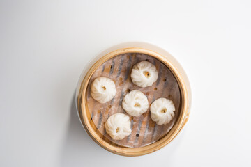 Chinese dim sum dumplings in bamboo basket isolated on white background