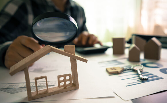Real estate or House Appraisal using magnifying glass over the model of a wooden house. Concept of House Search for housing and apartments.
