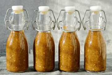 Bottles of chili hot sauce made from fermented chilies. Homemade Sriracha spicy sauce in bottles.