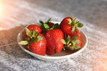 ripe red strawberry with leaves on a white plate. Vitamins