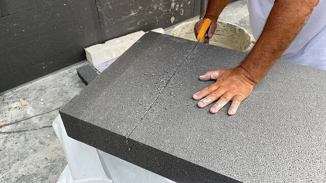 Man Cutting Thermal Insulation Panels with a Hand Saw in Slowmotion