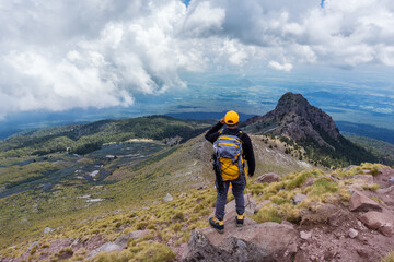 A hiker with a backpack standing on the top of the mountain