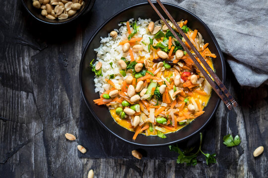 Peanuts garnished with yellow cauliflower and rice thai curry on table