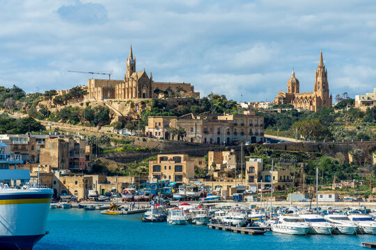 Yachts moored in sea by ghajnsielem parish church in city on sunny day Gozo, Malta