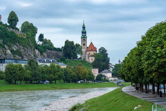 Austria, Salzburg State, Salzburg, Salzach river flowing through Mulln neighborhood with Pfarrkirche Mulln in background