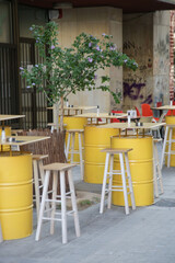 Hipster cafe in the street with yellow barrel tables and chairs, no people