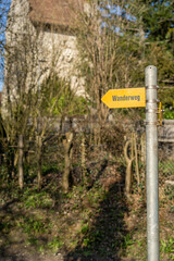 Single yellow signpost on pathway with castle in forest in background