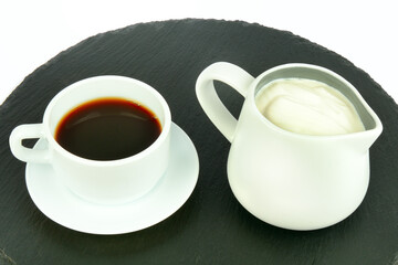 Coffee in a porcelain cup and milk cream in a jug isolated on a white.