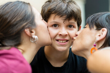 Closeup of an Upset little boy kissing by mom and sister