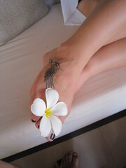 Fuß mit Plumeria-Blume und Flügel Tattoo