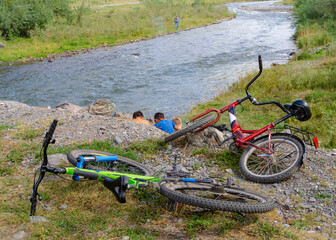 Fototapeta na wymiar The children have put their bikes down and are doing something on the riverbank
