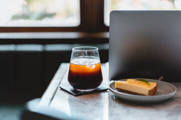 laptop computer, lemon Cheesecake and a cup of coffee in modern restaurant