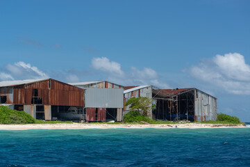 dilapidated hangars with ships on the shore of a coral island