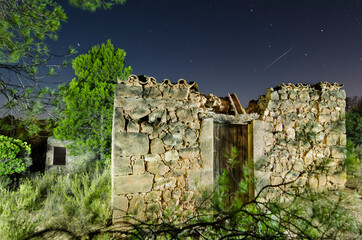 imagen nocturna de una casa de piedra medio derruida con estrellas en el cielo