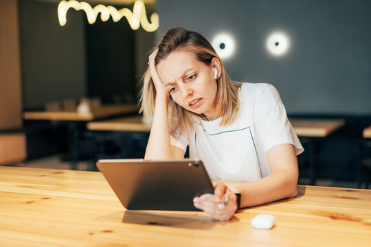 Upset Stressful Woman Looks At The Screen Of A Digital Tablet. Disappointment At Work, Bad News, Missed Deadlines And Plans.