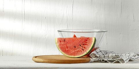 Fresh tasty watermelon on desk and white wall with shadows 