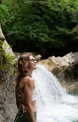 Young happy woman enjoing the waterfall