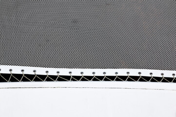 Part of a stretched white net with ropes threaded into loops on the catamaran hull.