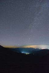 Night sky over the mountains with distand city lights