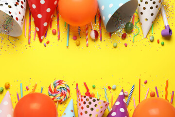 Flat lay composition with party decor and candies on yellow background, space for text