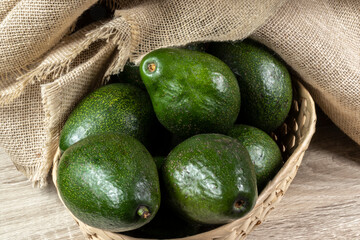 avocados fruits on the wooden table, with jute and black background in Brazil