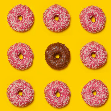 Pattern of pink doughnuts with single brown one in middle