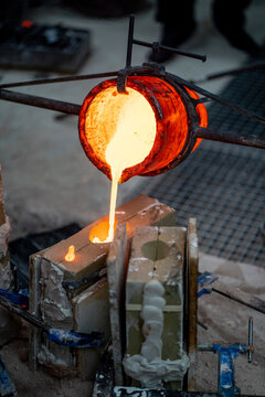 Furnace container pouring melted bronze at foundry