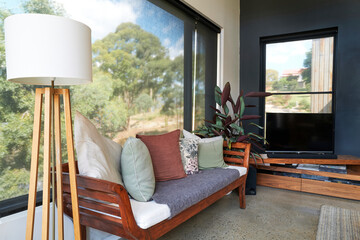 Wooden sofa with cushions by window in living room at home