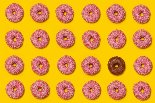 Pattern of pink doughnuts surrounding single brown one