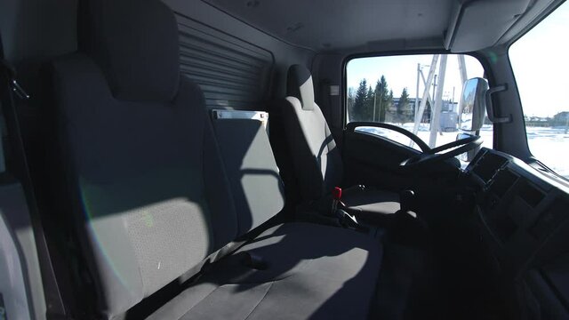 Empty spacious comfortable driver cabin of contemporary truck standing near power transmission lines in winter
