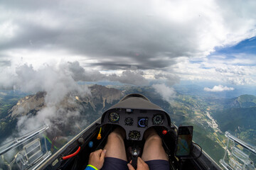 Ausblick aus einem Segelflug Cockpit über einer Bergregion mit Wolken