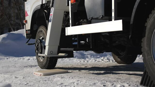 Installing hydraulic support of modern truck crane standing on snowy road on sunny winter day extreme close view