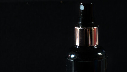 Closeup of a black spray bottle on dark background