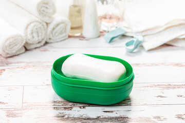 new soap on a green plastic soap dish, on a white wooden background.