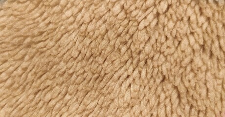 Smooth soft dirty light yellow color furry, fluffy and hairy artificial sheep skin plush fur wool rug background surface textured pattern for beauty and fashion concepts. Beautiful closeup top view.